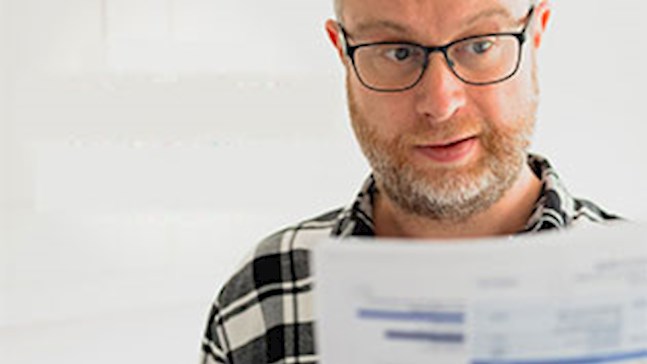 Man with glasses reading a high electricity bill
